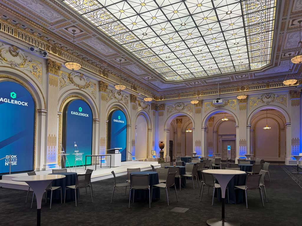 Ornate New York Stock Exchange Board Room prepared for an Eagle Rock event, with gilded arches and an illuminated glass ceiling.